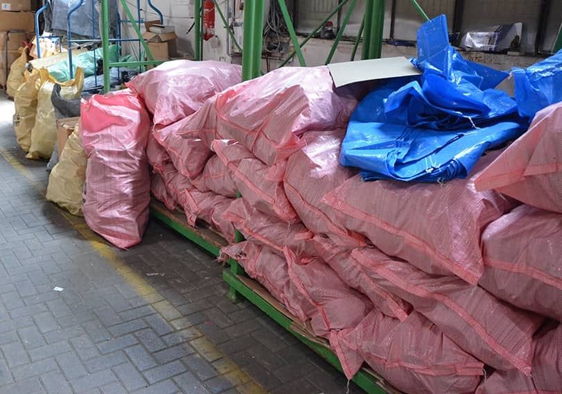 Pink and yellow bags filled with shoes and textiles